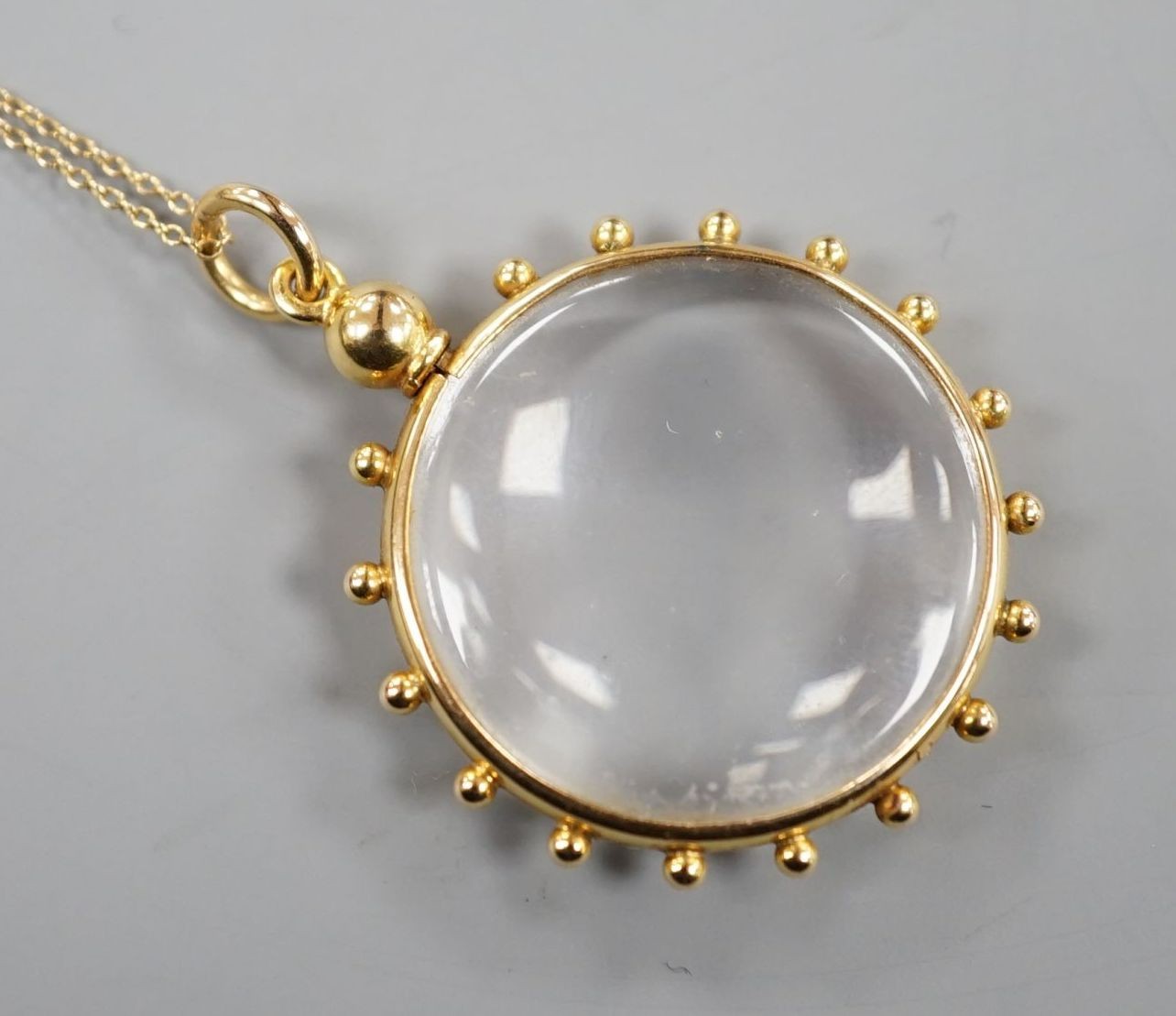 An early 20th century 15ct mounted eye glass pendant, 29mm, on a yellow metal fine link chain, gross 9.3 grams.